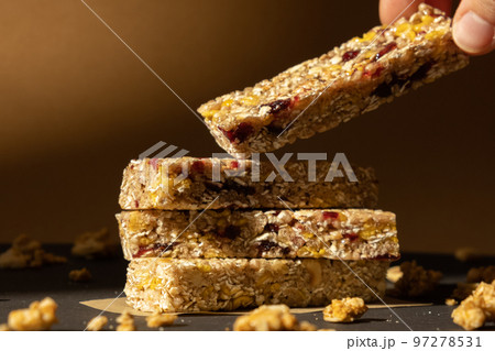 Woman takes Homemade Granola energy bar. Variety of protein granola breakfast bars, with nuts, raisins dried cherries and chocolate. Healthy nutrition eating Gluten free cereal dieting snack super Woman takes Homemade Granola energy bar. Variety of protein granola breakfast bars, with nuts, raisins dried cherries and chocolate. Healthy nutrition eating Gluten free cereal dieting snack super 97278531