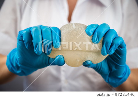 A plastic surgeon demonstrates the strength of silicone breast implants by squeezing them. 97281446