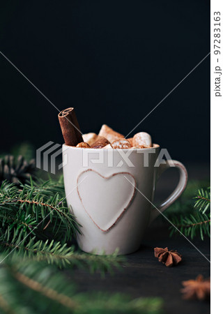 Winter Christmas beverage on the background of fir branches and garland lights on a wooden table. 97283163