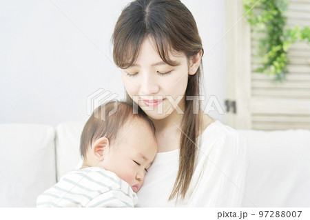 家で眠る赤ちゃんを抱っこする母親 97288007