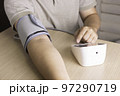 The man is checking blood pressure and heart rate with a digital pressure gauge by herself at home.  97290719