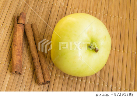 Ripe green Apple and cinnamon sticks on bamboo napkin Ripe green Apple and cinnamon sticks on bamboo napkin 97291298