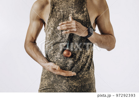 Christmas and the army. A golden Christmas ball hangs on the T-shirt of a young soldier standing on a white background Christmas and the army. A golden Christmas ball hangs on the T-shirt of a young soldier standing on a white background 97292393