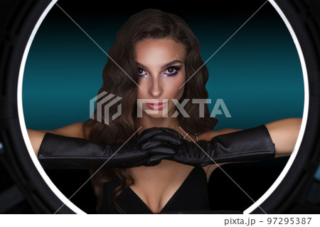 Female portrait of a young brunette girl with a beautiful evening make-up. The girl has gloves on her hands 97295387