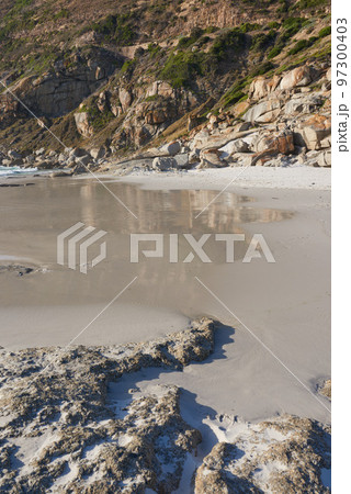 A rocky coastline at a beach in Cape Town with mountains in the background and copyspace. View of a shore with rocks at the ocean. Rocky coast of mountain sea washing over beach sand on a cold day A rocky coastline at a beach in Cape Town with mountains in the background and copyspace. View of a shore with rocks at the ocean. Rocky coast of mountain sea washing over beach sand on a cold day 97300403