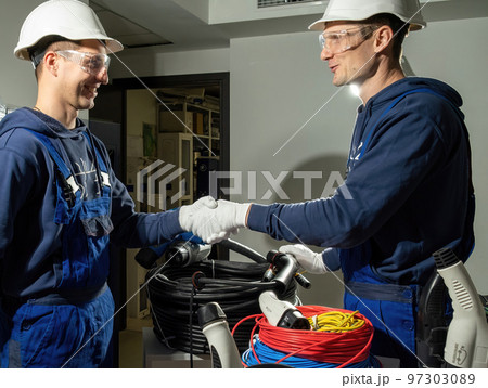Technicians shake hands and enjoy results of charging plug Technicians shake hands and enjoy results of charging plug 97303089