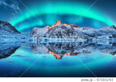 Northern lights over the mountain, sea coast, reflection in water 97303243