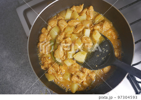 cooking chicken curry in a cooking pan  97304593