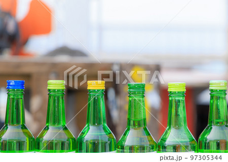 屋外のテーブルの上に並べられた緑色のビール瓶 97305344
