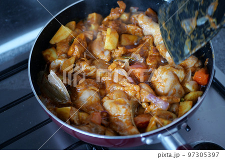 cooking chicken curry in a cooking pan  97305397