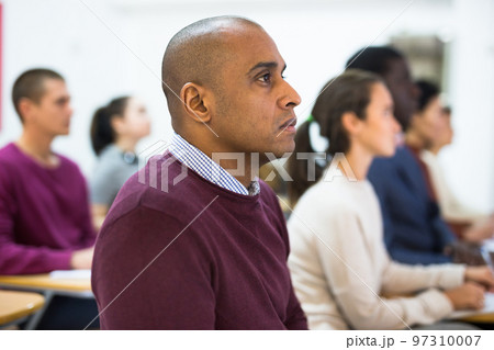 Group of students attentively listening to lecture in classroom Group of students attentively listening to lecture in classroom 97310007