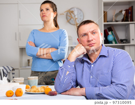 Upset man sitting at table after quarrel with wife at the home 97310095