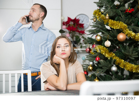Offended woman and man with phone on Christmas Eve 97310097