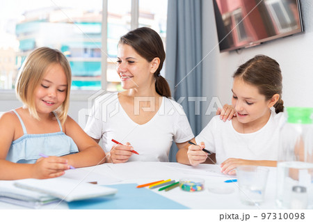 Young woman and two daughters drawing together 97310098