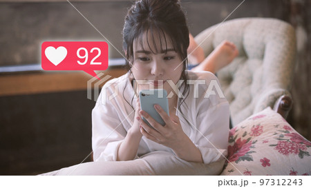 ソファーでスマートフォンを操作をする若い女性 ソファーでスマートフォンを操作をする若い女性 97312243