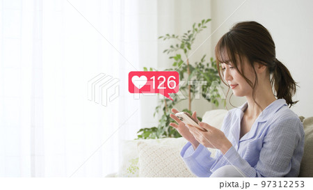 スマートフォンを操作をするパジャマ姿の若い女性 97312253