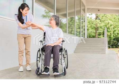 病院・介護施設で腕・肘のリハビリする車椅子に乗る高齢者と介護士（理学療法士・看護師） 97312744