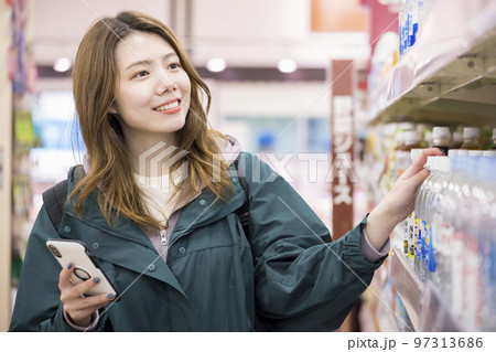 スーパーでスマホを見ながら買い物をする若い女性 97313686