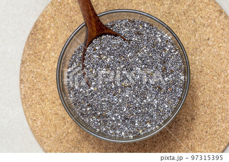 Healthy breakfast, Chia seeds or superfood in glass bowl with spoon on cardboard texture background 97315395