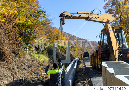 Installation of concrete drains precast in u-shapes on reconstruction road as means of draining surface Installation of concrete drains precast in u-shapes on reconstruction road as means of draining surface 97315690