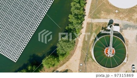 Sewage treatment facilities with aeration water tanks in modern wastewater treatment plant near floating solar panels cell platform system on lake 97315869