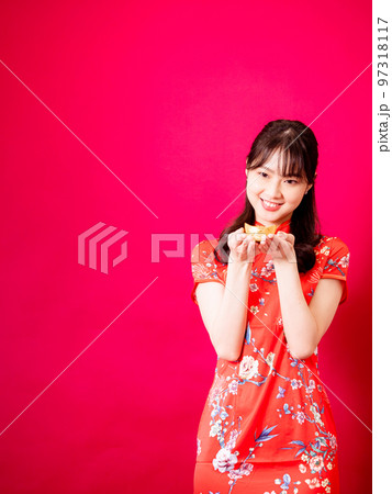 赤い背景に旧正月を祝うための金のインゴットを示す伝統的なチャイナドレスを着た幸せなアジアの若いアジア 赤い背景に旧正月を祝うための金のインゴットを示す伝統的なチャイナドレスを着た幸せなアジアの若いアジア 97318117