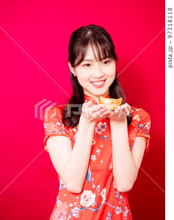 赤い背景に旧正月を祝うための金のインゴットを示す伝統的なチャイナドレスを着た幸せなアジアの若いアジア 赤い背景に旧正月を祝うための金のインゴットを示す伝統的なチャイナドレスを着た幸せなアジアの若いアジア 97318118