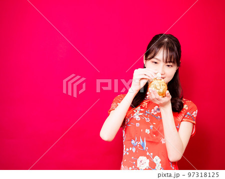 赤い背景に旧正月を祝うための金のインゴットを示す伝統的なチャイナドレスを着た幸せなアジアの若いアジア 97318125