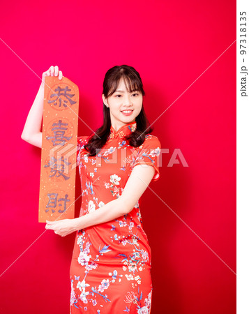 伝統的なチャイナドレスを着たアジアの若い女性は、赤い背景に新年を