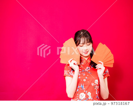 赤の背景にアンパオまたは赤のパケットの金銭的贈り物(お年玉)を保持している伝統的なチャイナ ドレス 97318167