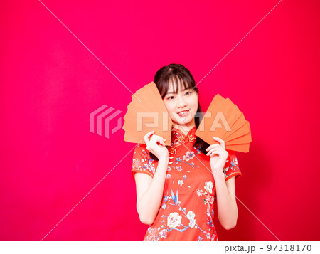 赤の背景にアンパオまたは赤のパケットの金銭的贈り物(お年玉)を保持している伝統的なチャイナ ドレス 97318170