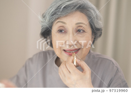 鏡を見ながら口紅を塗るグレイヘアのシニア女性 97319960