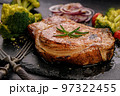 Grilled meat and vegetables. Appetizing pork loin and broccoli on a black stone cutting board. Close-up 97322455