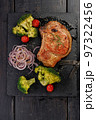 Grilled meat and vegetables. Appetizing pork loin and broccoli on a black stone cutting board. Top view. Vertical shot. Copy space 97322456