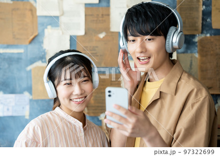ヘッドホンでスマホ音楽を聴く若いカップル 97322699