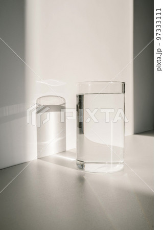 Transparent glass of water in the sunlight on a white background Transparent glass of water in the sunlight on a white background 97333111