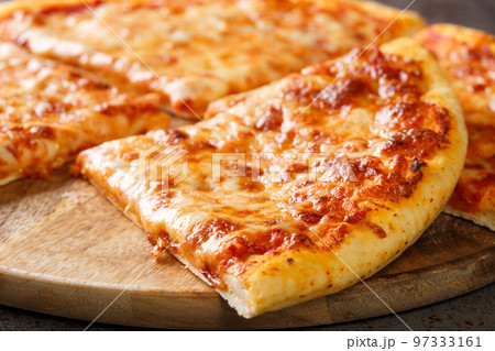 Delicious crispy New York style pizza with melted cheese and base tomato sauce close-up on a wooden board. Horizontal Delicious crispy New York style pizza with melted cheese and base tomato sauce close-up on a wooden board. Horizontal 97333161