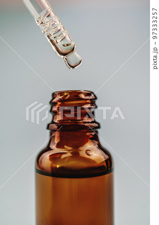 Pipette with cosmetic oil over a brown bottle 97333257