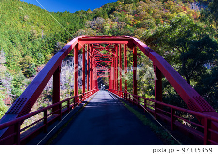 ダムに架かる対岸に渡る橋の赤い鉄骨 97335359