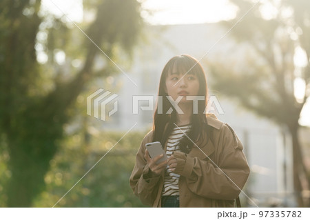 屋外でスマホを操作する若い女性 屋外でスマホを操作する若い女性 97335782