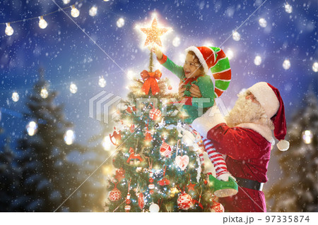 Santa and elf decorating Christmas tree. 97335874