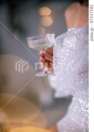The hands of a woman hold a glass of champagne on a background of golden beke. The concept of the holiday, Christmas, new year, birthday. The hands of a woman hold a glass of champagne on a background of golden beke. The concept of the holiday, Christmas, new year, birthday. 97337582