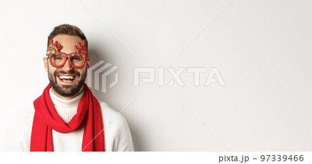 Christmas, New Year and celebration concept. Close-up of happy bearded man smiling, wearing party glasses and red scarf, white background Christmas, New Year and celebration concept. Close-up of happy bearded man smiling, wearing party glasses and red scarf, white background 97339466