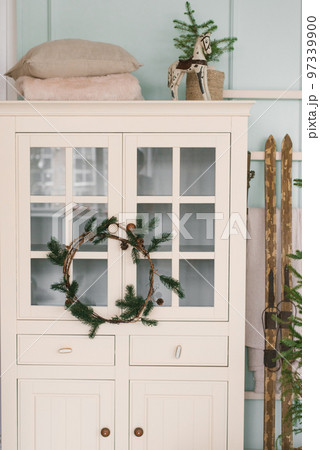 White wardrobe with a Christmas wreath, skis and decor in the living room of the house 97339900