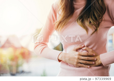 Asian young female suffers from stomachache after eating spoiled food, Abdominal pain from menstrual cramps, Sick woman unhappy having stomach ache digestive problem at home 97339969