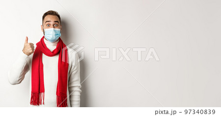 Covid-19, lockdown and quarantine concept. Amazed and satisfied man buyer in medical mask showing thumb-up, looking excited, like something good, white background Covid-19, lockdown and quarantine concept. Amazed and satisfied man buyer in medical mask showing thumb-up, looking excited, like something good, white background 97340839