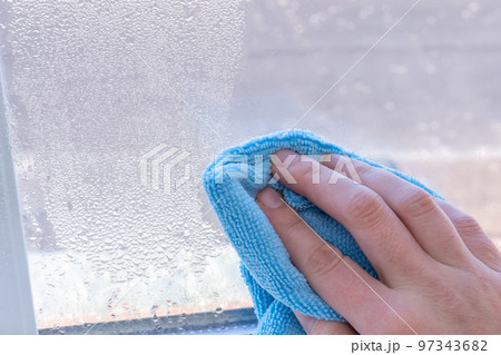 Condensation on windows in winter, wiping with a dry cloth Condensation on windows in winter, wiping with a dry cloth 97343682