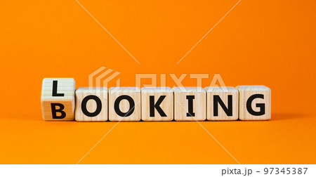 Looking and booking symbol. Turned the wooden cube and changed the word 'looking' to 'booking'. Beautiful orange background, copy space. Business, looking and booking concept. 97345387