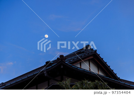 大きな家の屋根の上に浮かぶ月齢11の月 97354404
