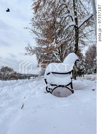 Snow-covered bench overlooking the embankment and the city under lots of snow in the morning in natural light 97357187